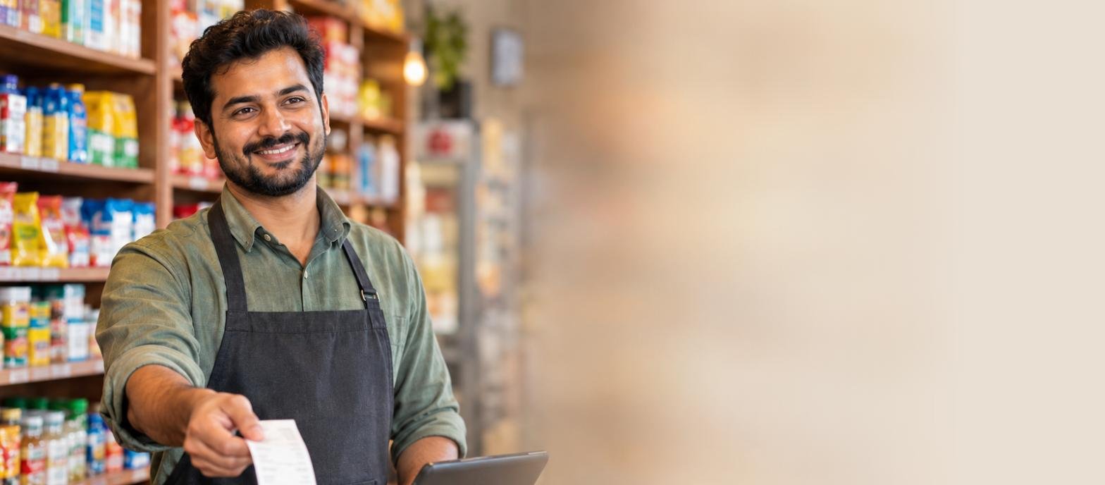 A shopkeeper handing a printed bill across the counter